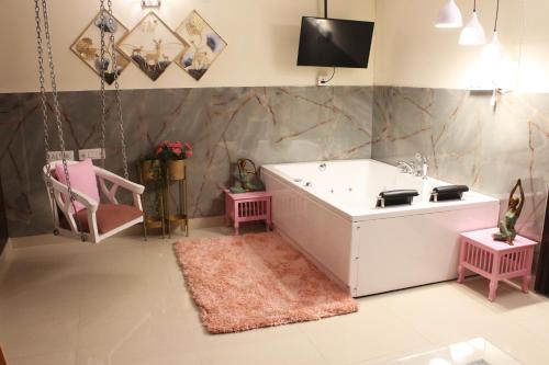 ein Badezimmer mit einer Badewanne und einem TV an der Wand in der Unterkunft Modern Jacuzzi Spa Tub 1BHK Suite South Delhi (3) in Neu-Delhi