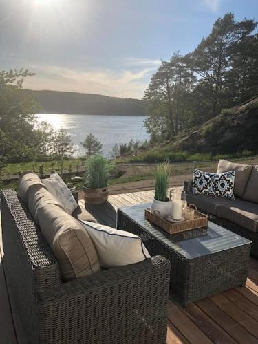 a patio with a couch and a table with a view of the water at Sommerhus ved Iddefjorden in Halden