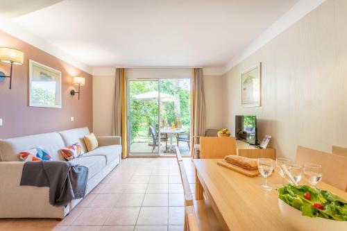a living room with a couch and a table at Résidence Pierre & Vacances le Hameau de la Pinède in Hyères