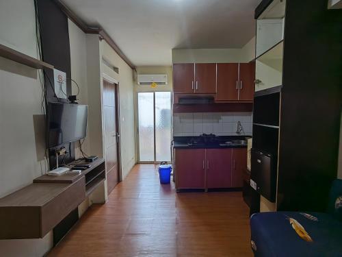 a kitchen with brown cabinets and a wooden floor at Cibubur Village By Arsakha Property Management in Cibubur