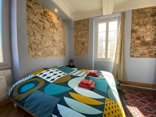 a bedroom with a colorful bed with two red pillows on it at Résidence Verdi - Appartements meublés en centre ville in Bédarieux
