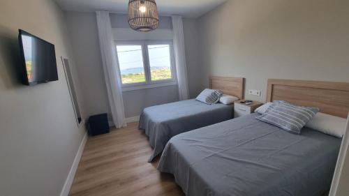 ein Schlafzimmer mit zwei Betten und einem Fernseher und einem Fenster in der Unterkunft Casa Aios in Sanxenxo