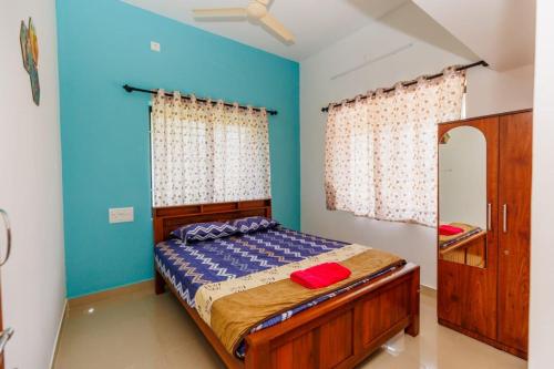 a bedroom with a bed with a blue wall at Galaxy Homestays in Malpe