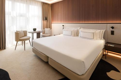 a bedroom with a large white bed and a table at Hotel Meliá Bilbao in Bilbao