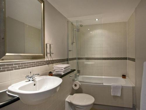 a bathroom with a sink and a toilet and a tub at OYO The Red Lion Hotel in Luton