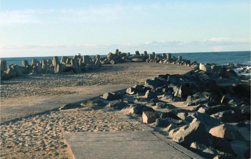 a group of rocks on a beach with the ocean at Hytte 22 in Thyborøn