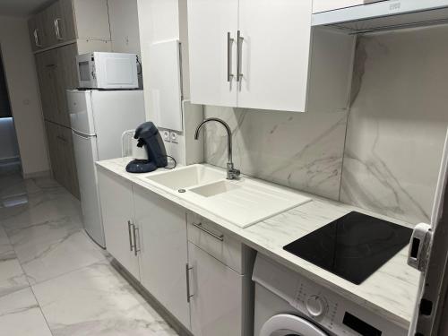 une cuisine blanche avec un évier et un micro-ondes dans l'établissement Studio vue sur le port, à Mauguio