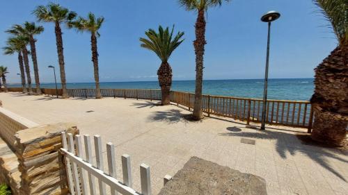 a boardwalk with palm trees and the ocean at CHALET A 5 METROS DEL MAR.Wifi gratis in Murcia