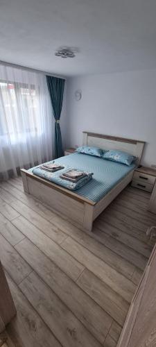 a large bed in a bedroom with a wooden floor at Alexandra si Adan in Dubova