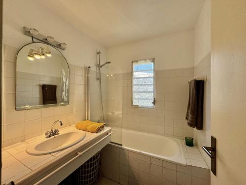 a bathroom with a sink and a tub and a mirror at Grand appartement confortable 2 chambres proche marina in Saint-François