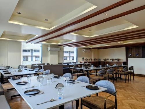 a dining room with white tables and chairs at Hotel Majestic By NxtJen Hospitality in Silvassa