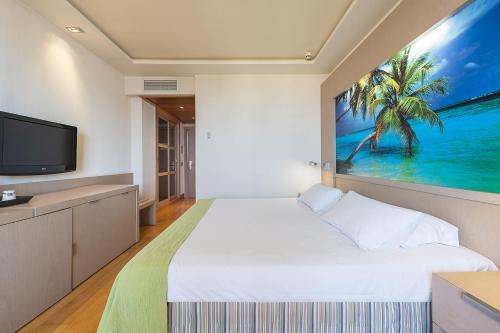 a bedroom with a large white bed and a tv at Hotel Nelva in Murcia