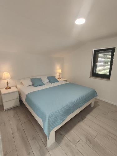 a bedroom with a bed with blue sheets and a window at Villa Lucija in Ploče