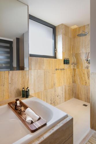 a bathroom with a tub and a shower with a window at Hotel Meliá Bilbao in Bilbao