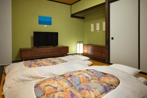 a bedroom with two beds and a flat screen tv at IKOI Villa in Karuizawa