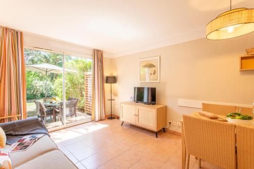 a living room with a television and a dining room at Résidence Pierre & Vacances le Hameau de la Pinède in Hyères