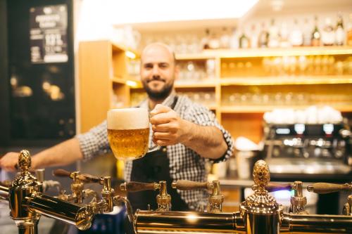 a man holding a glass of beer at a bar at Hotel Purkmistr in Plzeň