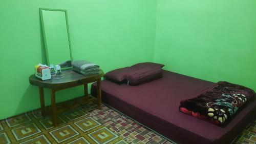 a room with a bed and a table with a mirror at Wisma PO'ONG in Ruteng