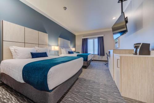 a hotel room with two beds and a flat screen tv at Hotel Peppertree Bend, BW Premier Collection in Bend
