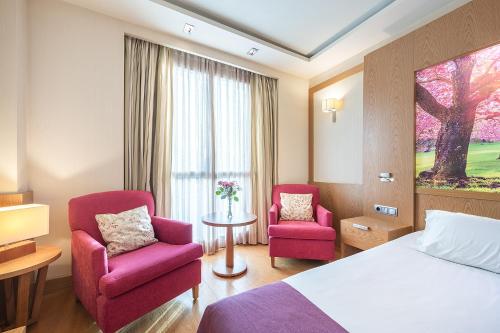 a hotel room with two chairs and a bed at Hotel Nelva in Murcia