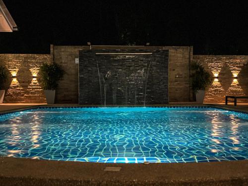 a swimming pool at night with a fountain at Mangoes Pattaya in Na Jomtien