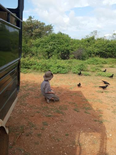 a man sitting on the ground next to a bus at Jungle Lodge in Udawalawe