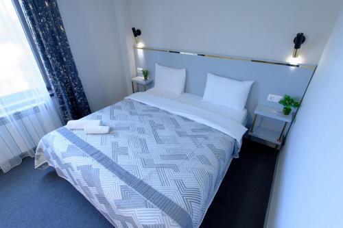 een slaapkamer met een groot bed met witte lakens en kussens bij Grand Aura Hotel in Alma-Ata