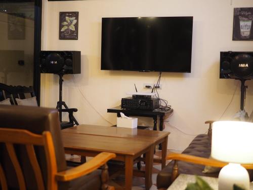 a living room with a table and a tv on the wall at Mangoes Pattaya in Na Jomtien