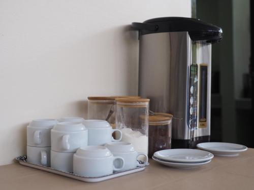 a counter with cups and plates and a coffee maker at Mangoes Pattaya in Na Jomtien