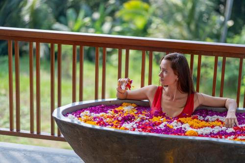 a woman sitting in a large tub of flowers at Unagi Wooden Villas by Emana in Ubud