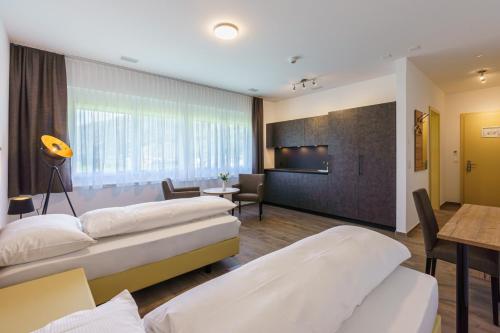 a hotel room with two beds and a living room at Hotel B&B in Gampel