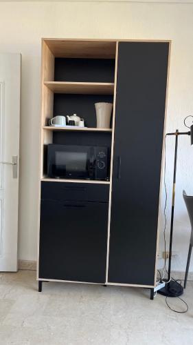 une armoire avec un réfrigérateur noir dans une pièce dans l'établissement Le plein soleil, à Ajaccio