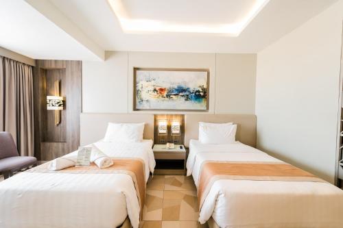 a hotel room with two beds and a chair at Zuri Hotel in Iloilo City