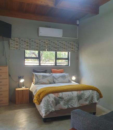 a bedroom with a bed and a window at Gecko Cottages in Hectorspruit