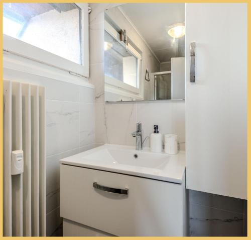 une salle de bain blanche avec un lavabo et une fenêtre dans l'établissement Chez Norah I Annemasse, à Annemasse