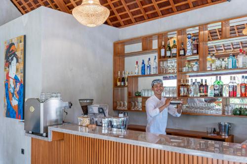 a woman standing behind a bar in a restaurant at Unagi Wooden Villas by Emana in Ubud