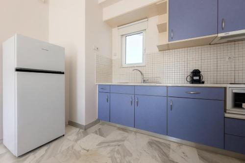 una cucina con mobili blu e un frigorifero bianco di Karystos Mare Apartments a Karistos