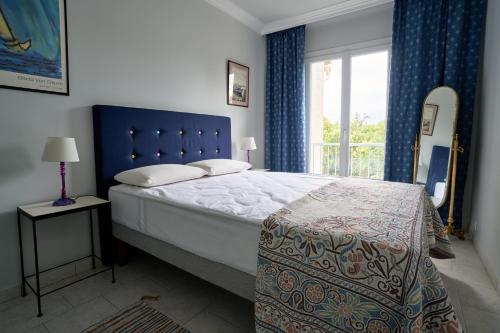 a bedroom with a bed with a blue headboard and a window at Maison familiale avec jacuzzi, quartier calme in Avignon