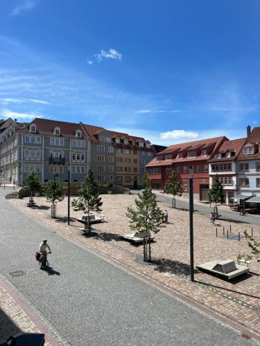 a person riding a scooter down a street with buildings at CozyHome Hauptmarkt Apartments in Gotha