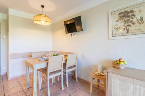 a kitchen and dining room with a table and chairs at Résidence Pierre & Vacances le Hameau de la Pinède in Hyères