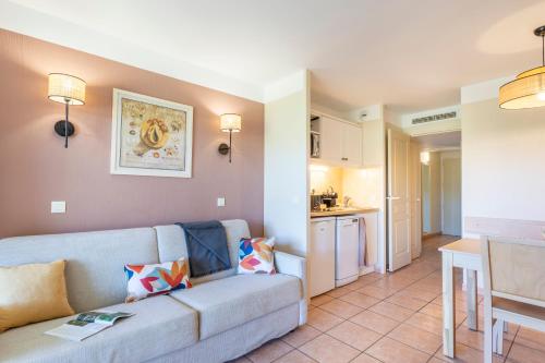 a living room with a couch and a kitchen at Résidence Pierre & Vacances le Hameau de la Pinède in Hyères