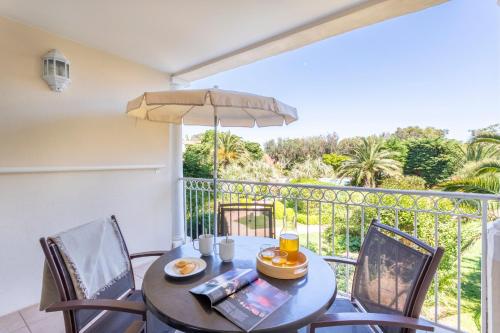 a table with chairs and an umbrella on a balcony at Résidence Pierre & Vacances le Hameau de la Pinède in Hyères