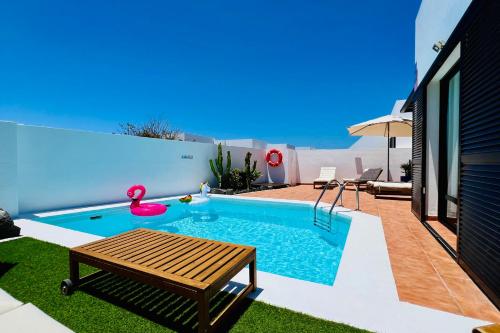 Una piscina con una mesa y un banco en un patio. en El Salto 37 - Rinnovata 2023, Piscina Riscaldata, Sole tutto il giorno! Wi-Fi, Massima privacy, Ottima posizione, en Playa Blanca