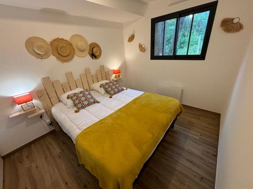 a bedroom with a bed with a yellow blanket at Maison du Bois, pinède et océan in Saint-Jean-de-Monts