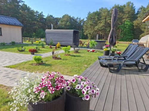 a deck with flowers and a bench and an umbrella at Jūras dzintars in Ainaži