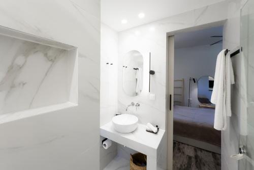 a white bathroom with a sink and a mirror at Karystos Mare Apartments in Karistos