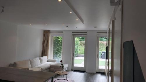 a living room with a white couch and windows at GelreDroom in Arnhem