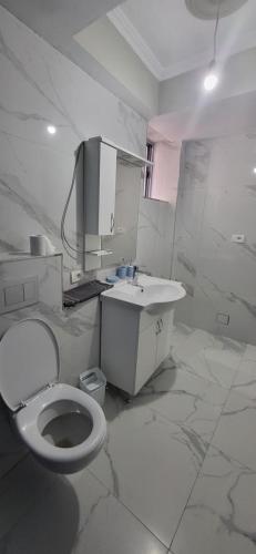 a white bathroom with a toilet and a sink at Jon rooms in Himare