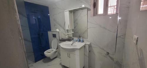 a white bathroom with a toilet and a sink at Jon rooms in Himare
