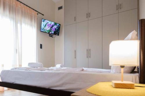 a bedroom with a bed and a tv on the wall at Effie's Maisonette with Detached Studio in Amaliápoli